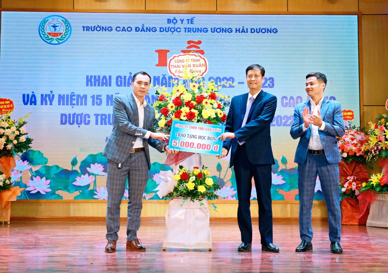 Giám đốc, phó giám đốc công ty TNHH Thái Vạn Xuân trao quà cho lãnh đạo nhà trường (giữa).